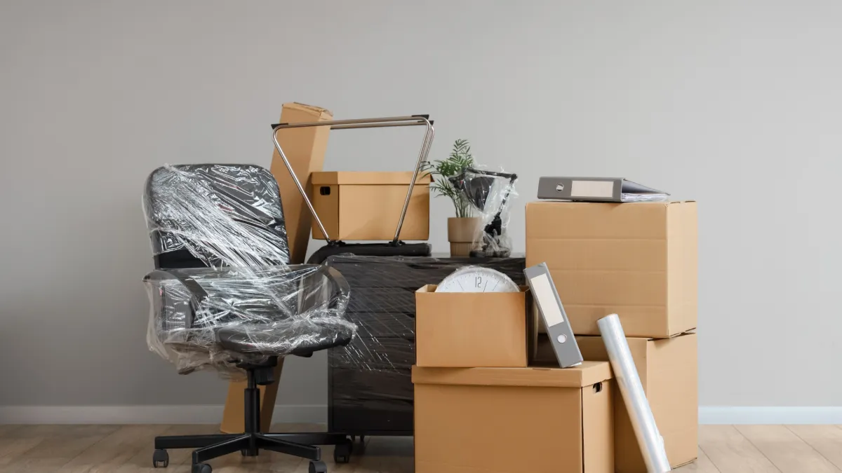 Büroumzug nach Volketswil – in Folie geschützte Bürostühle, Schreibtische und Umzugskartons bereit für den Firmenumzug in die Industriezone