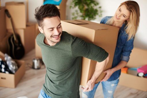 couple-carrying-heavy-moving-boxes-together-min